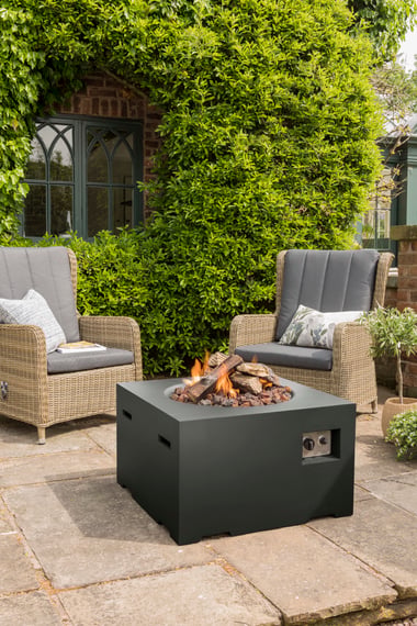 Happy Cocoon 76cm square black steel fire pit on a patio surrounded by garden furniture