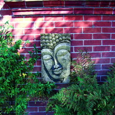 Stone Buddha Relief Wall Plaque mounted on garden wall